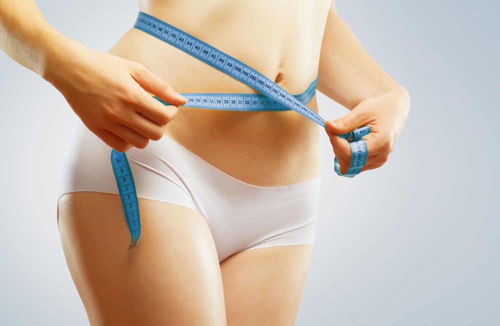 A woman measures her waist